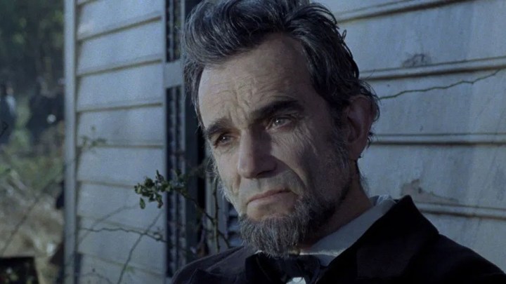 Daniel Day-Lewis como Abraham Lincoln se senta e olha em Lincoln.