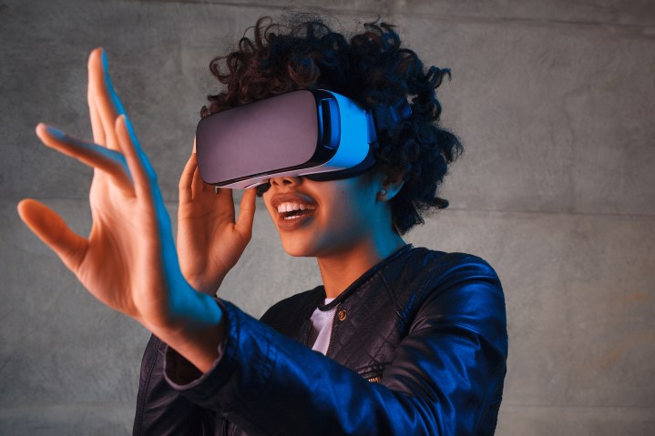 A woman wearing a VR headset is reaching out.