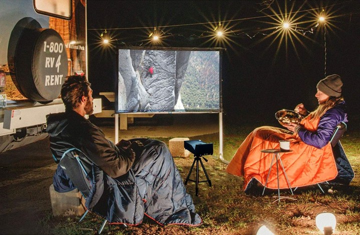 A couple watching a movie on the Elite Screens Yard Master 2 projector screen outside.