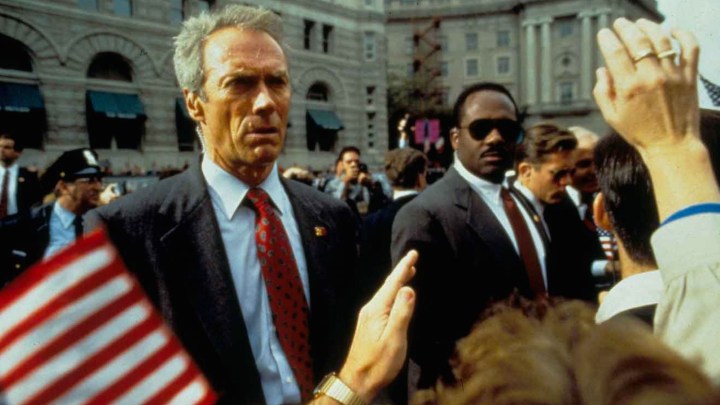 Clint Eastwood stands next to men in front of a crowd.