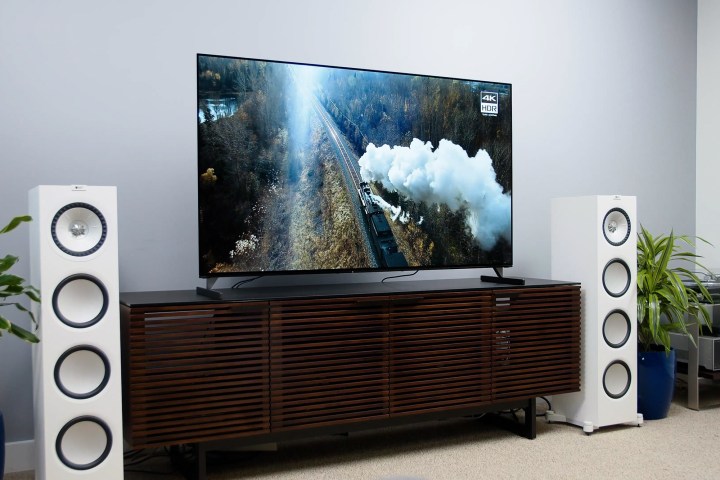 A Sony Bravia XR A90J 4K OLED TV on a media console flanked by two white surround sound tower speakers. 