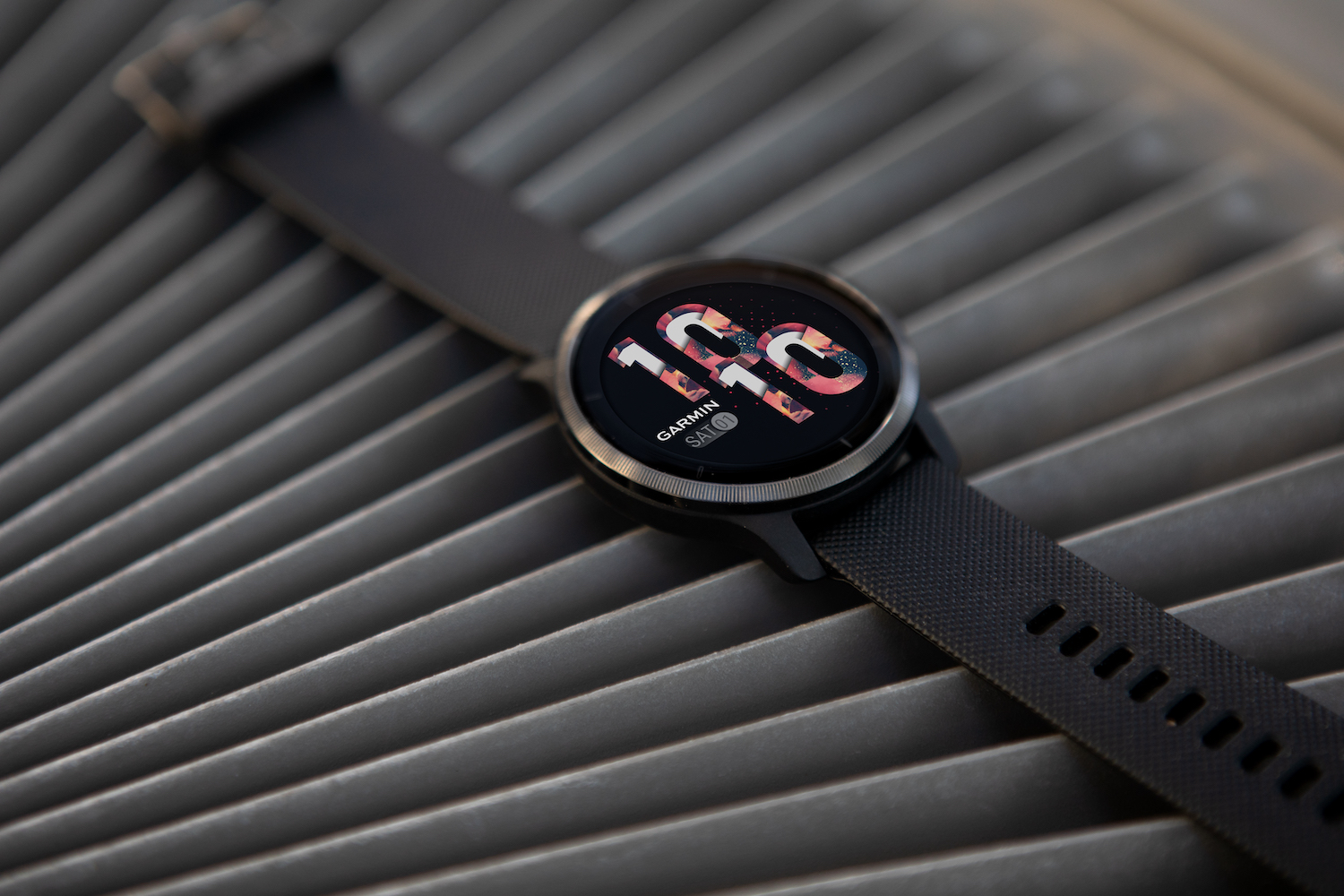 O smartwatch Garmin Venu 2s, colocado sobre uma superfície ondulada.