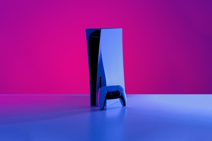 Una PS5 in piedi su un tavolo, con luci viola intorno.