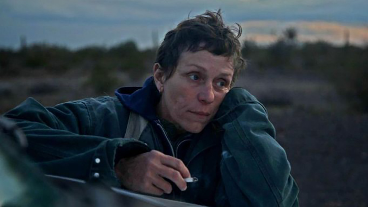 Frances McDormand está sentada com o rosto agachado na mão em uma cena de Nomadland.