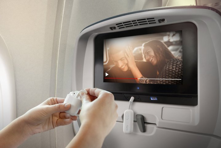 Mãos conectando o Twelve South AirFly Pro ao sistema de entretenimento de um avião.