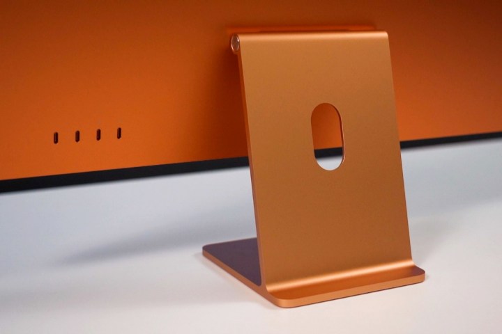 An orange 24-inch iMac seen from behind, with a focus on its hinge and ports.