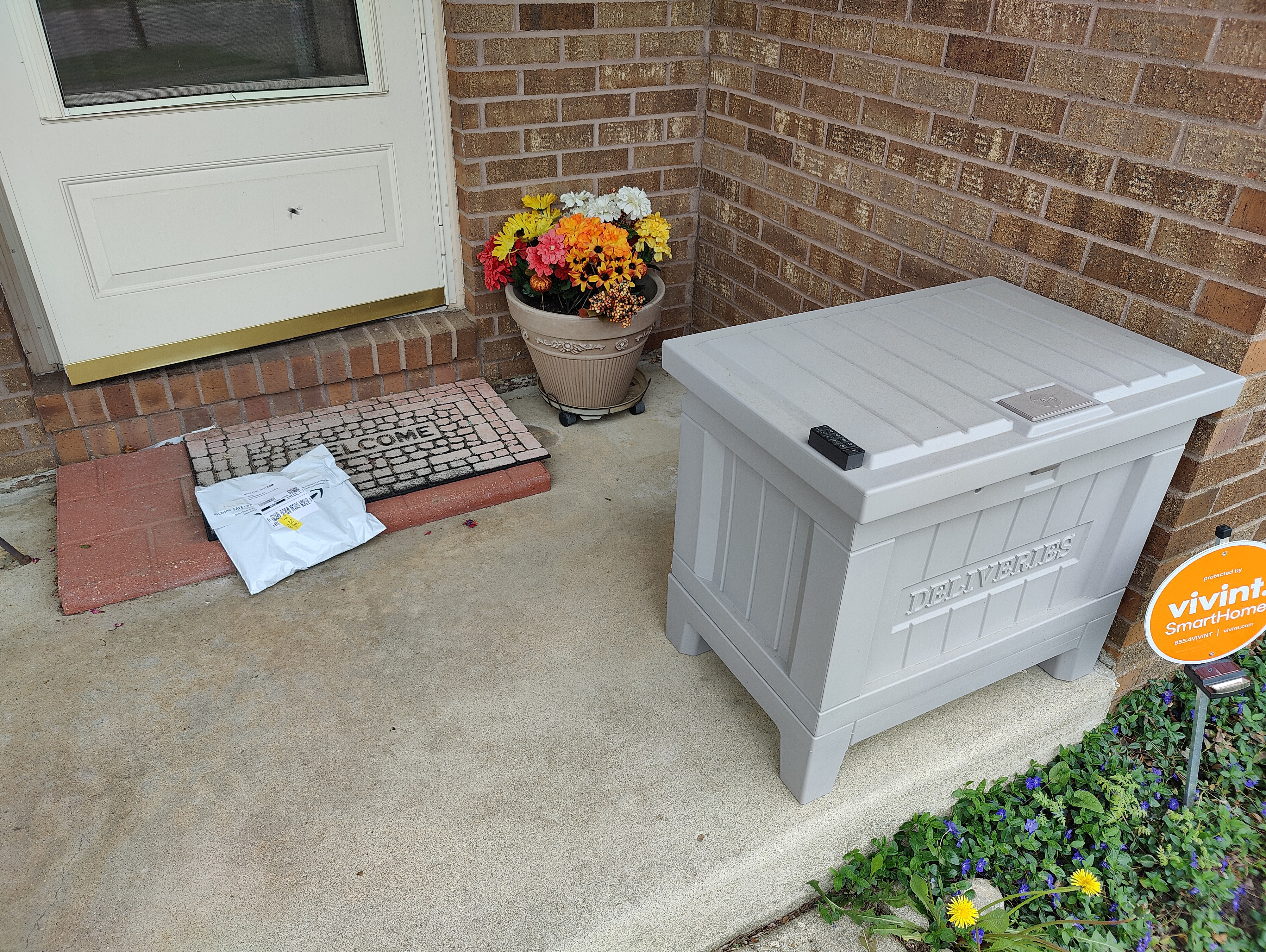 An Amazon package sits on the front porch near the Yale Smart Delivery box,.