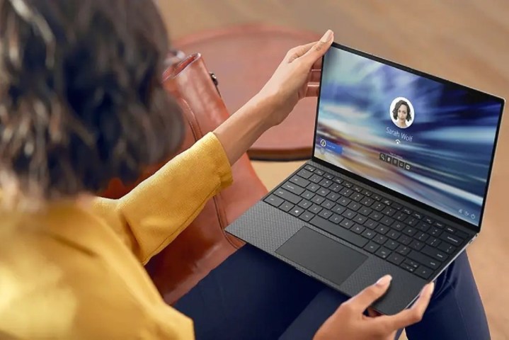 Person sitting and holding a Dell XPS 13 laptop on their lap.