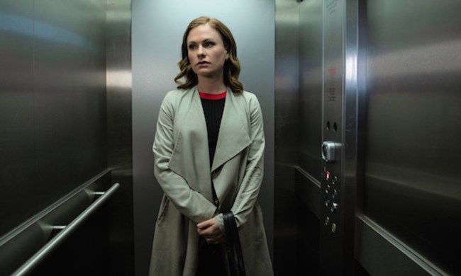 The lead character from Flack standing in an elevator with a long beige coat.