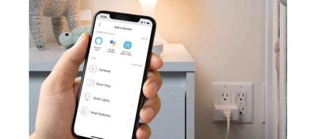 Kasa Smart Plug in a wall socket with a phone showing the Kasa app.