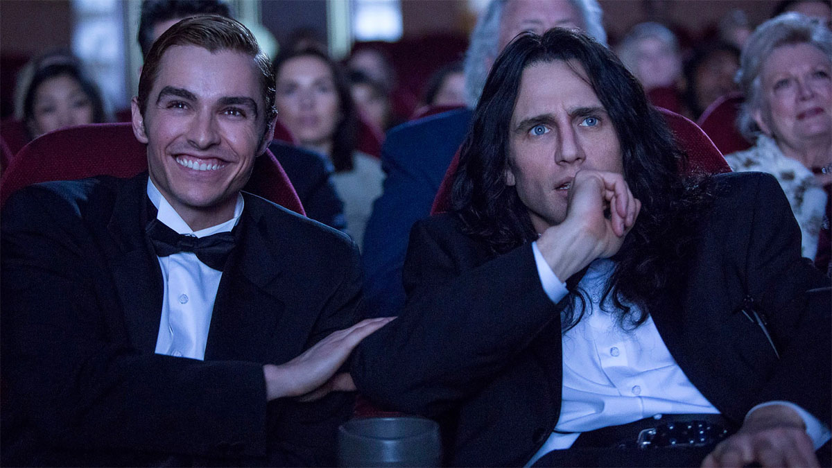 Two men in suits sit in a theater.