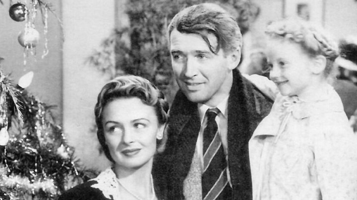 Jimmy Stewart como George Bailey sosteniendo a su esposa en un brazo y a su hija en el otro en "It's A Wonderful Life".