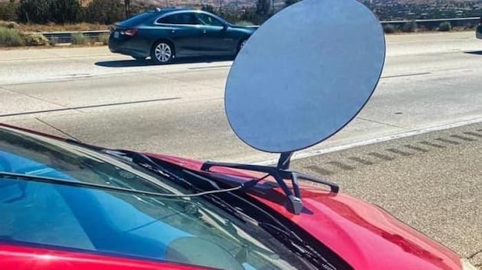 A satellite dish bolted to a car's hood.