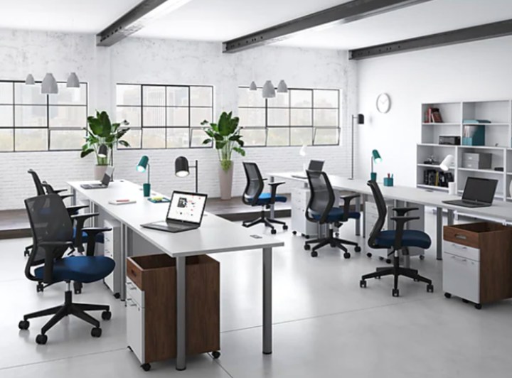 A bright office with multiple chairs at long desks.