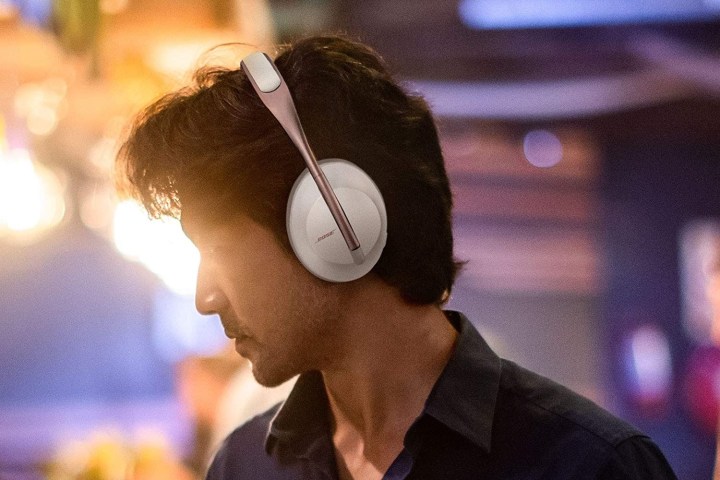 A man wearing Bose 700 headphones with a moody background.
