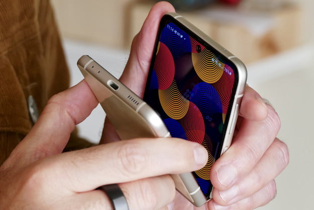 Un Samsung Galaxy Z Flip 3 color oro tenuto in mano mentre è parzialmente chiuso.