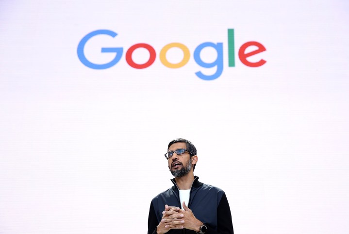 Sundar Pichai stands in front of a screen showing the Google logo.