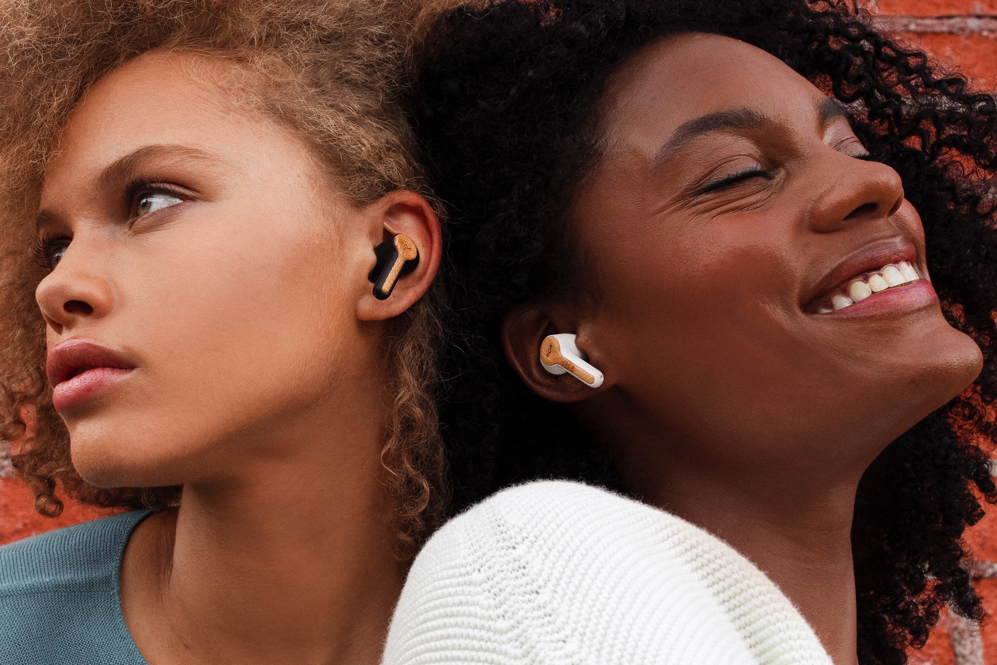 Two women wearing House of Marley Rebel True Wireless Earbuds.