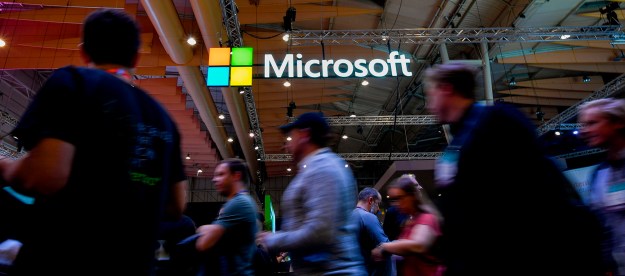 Attendees walk past the Microsoft logo during the Web Summit in Lisbon.