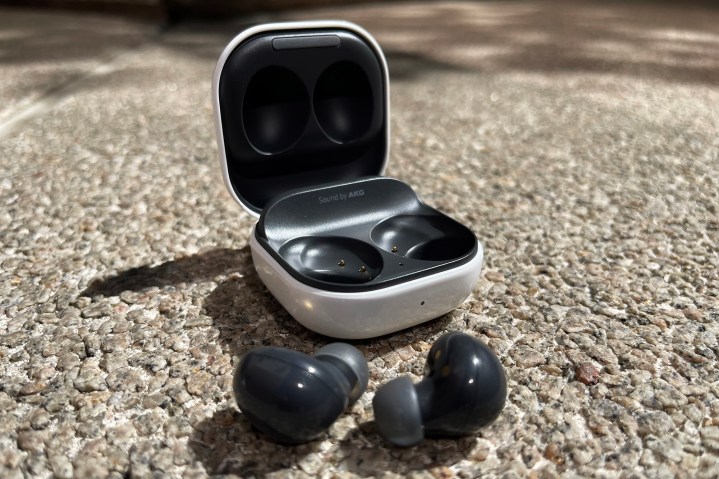 Samsung Galaxy Buds 2 and their case sitting on the ground with the headphones sitting in front.