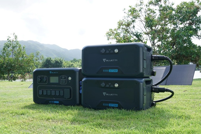 BLUETTI AC300 solar power station and B300 batteries in a field.