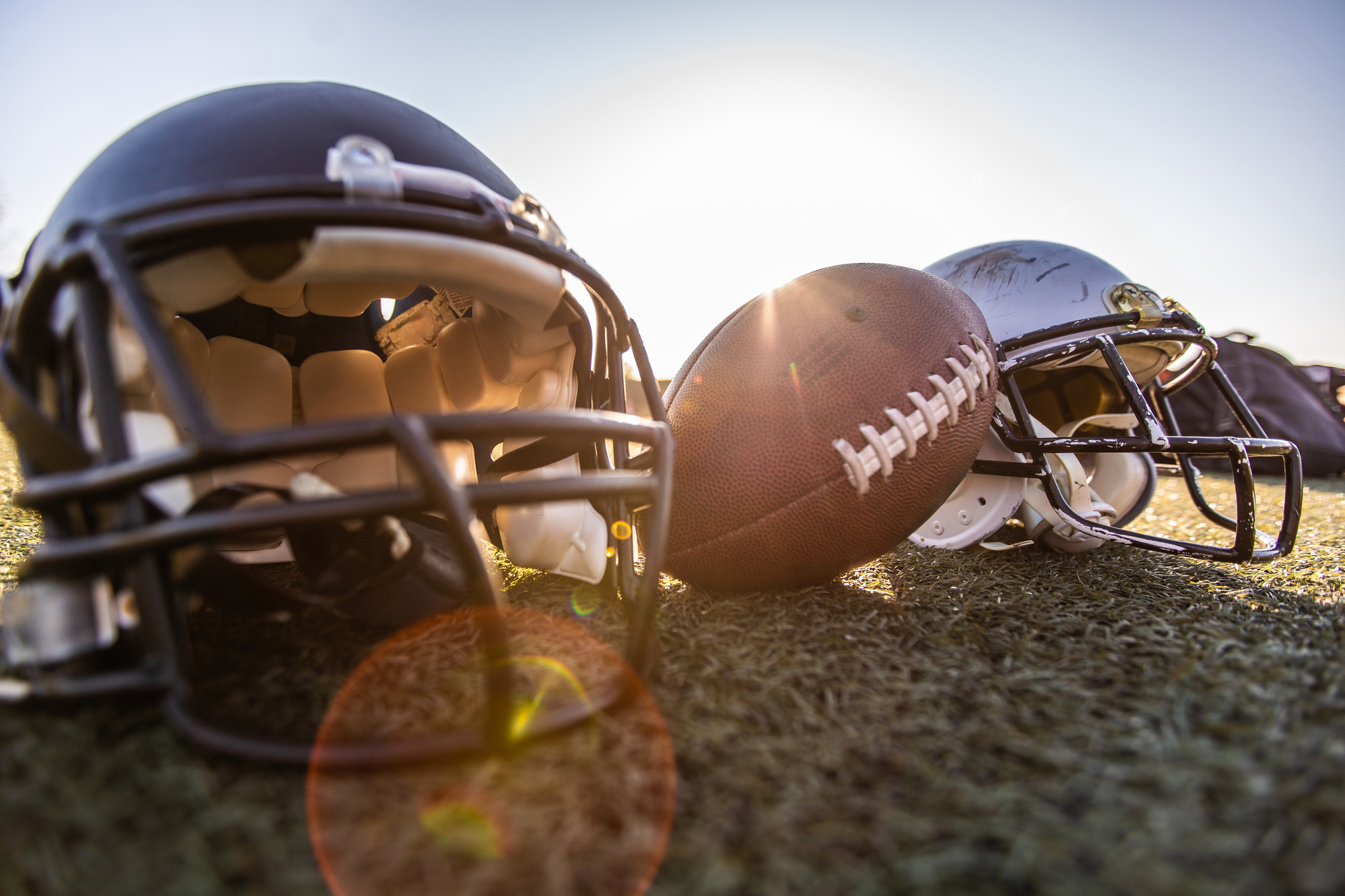A football rests between two helmets.