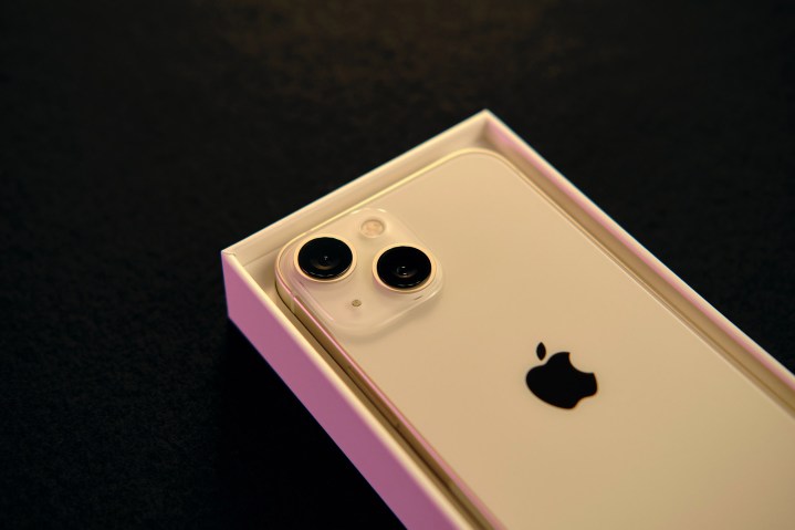 iPhone 13 Mini tendido dentro de su caja original sobre una superficie negra.