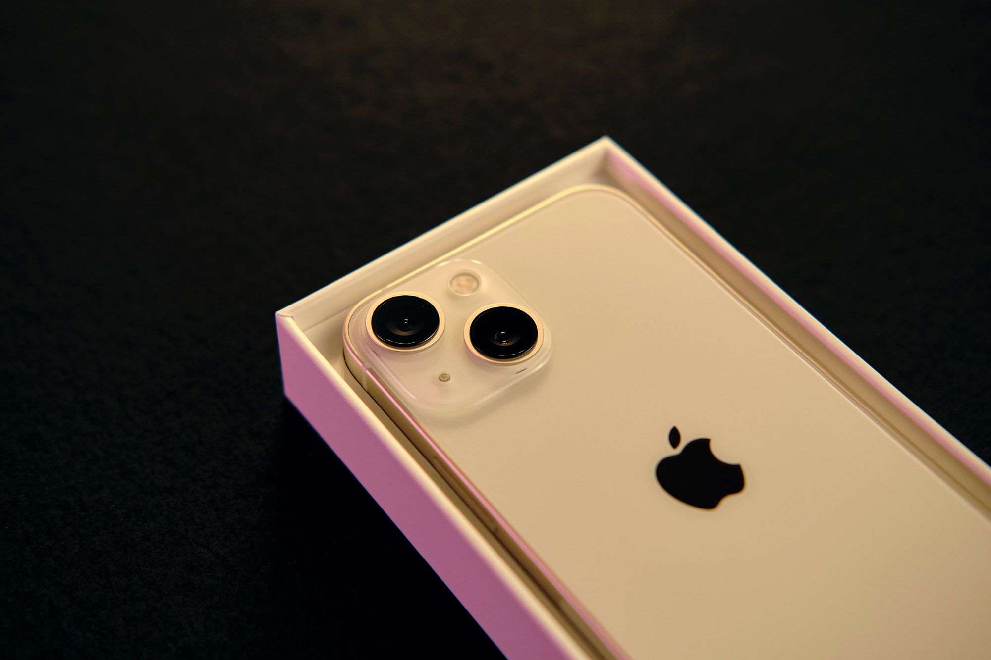iPhone 13 Mini dentro de su caja original sobre una superficie negra.