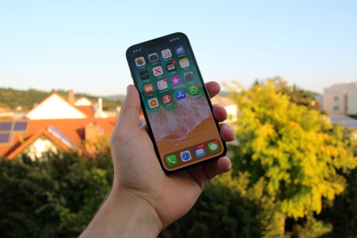 iPhone 13 मिनी पकड़े हुए व्यक्ति।