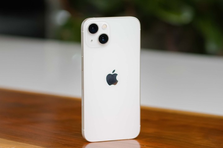 iPhone 13 in posizione verticale sul tavolo di legno.