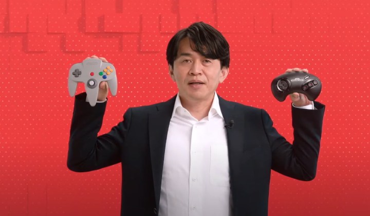 Yoshiaki Koizumi holding the N64 and Sega Genesis controllers for Nintendo Switch.