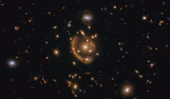 La estrecha galaxia que se curva elegantemente alrededor de su compañera esférica en esta imagen es un ejemplo fantástico de un fenómeno verdaderamente extraño y muy raro. Esta imagen, tomada con el Telescopio Espacial Hubble de la NASA/ESA, muestra a GAL-CLUS-022058s, ubicado en la constelación de Fornax (El Horno) en el hemisferio sur. GAL-CLUS-022058s es el anillo de Einstein más grande y uno de los más completos jamás descubiertos en nuestro Universo.