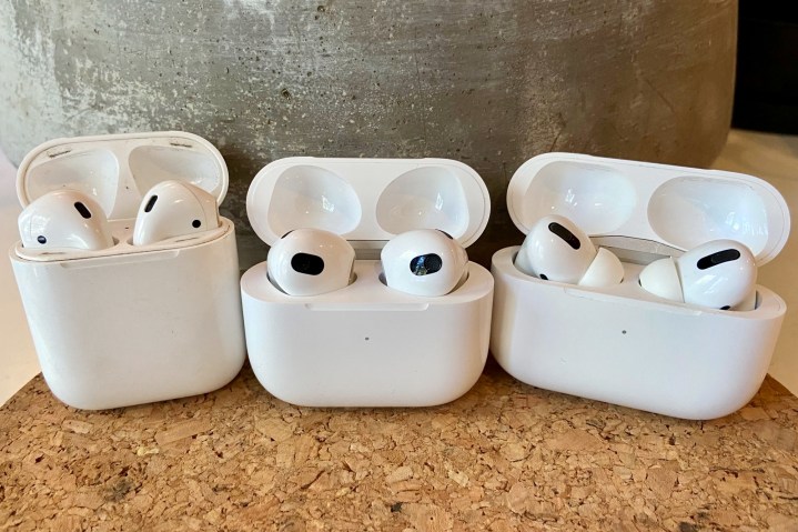 AirPods 3, AirPods, and AirPods Pro sitting in their charging cases.