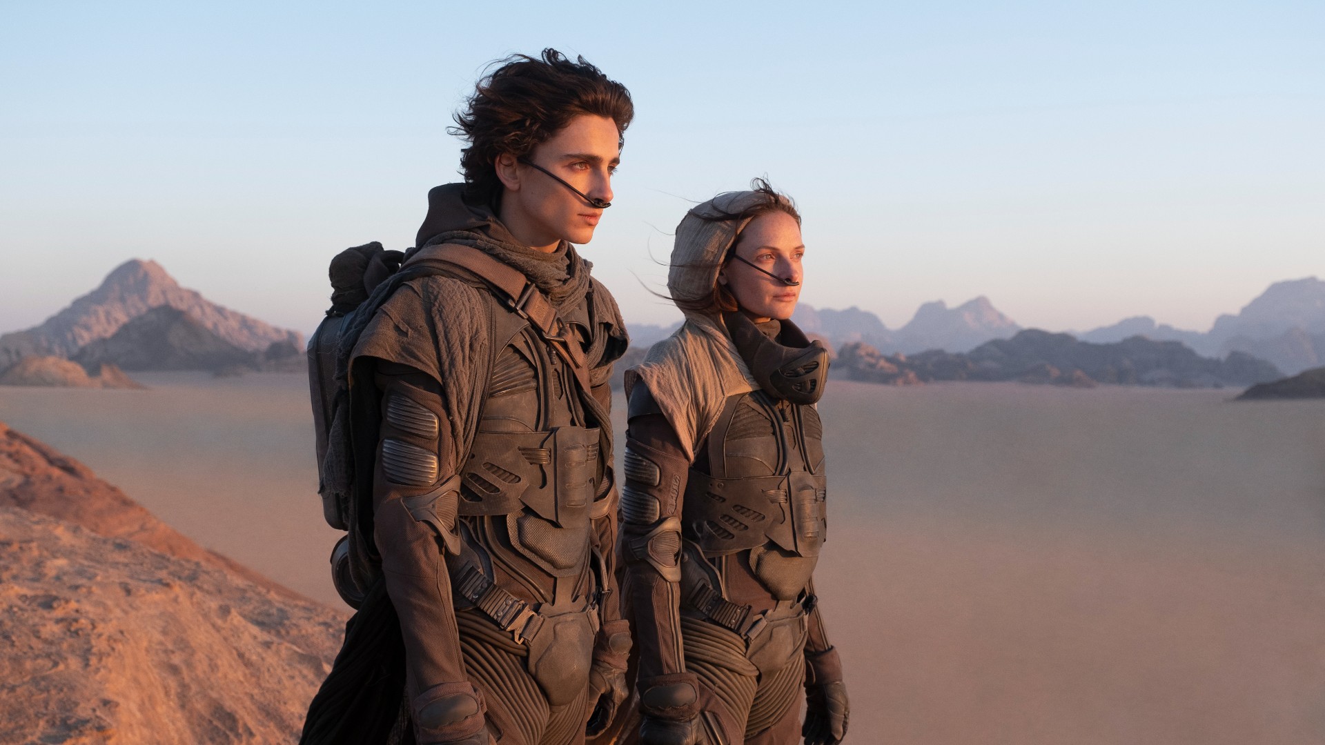 Timothee Chalamet e Rebecca Ferguson contemplam o deserto em Dune.