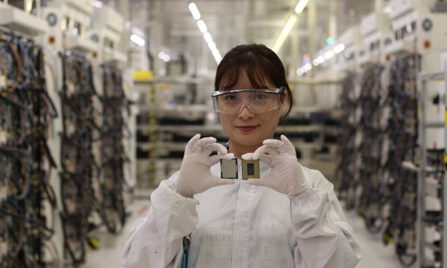 An engineer smiles as she holds up two processor chips.