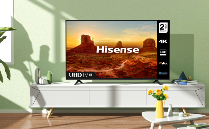 Una TV 4K Hisense Classe A6G da 70 pollici su una console multimediale bianca.  La luce del sole e le ombre attraversavano il soggiorno.