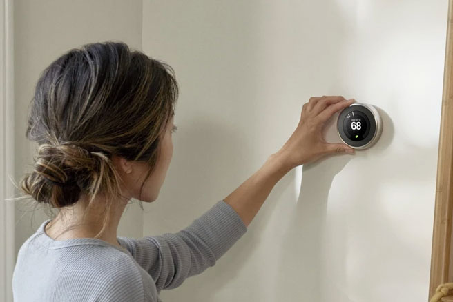 Photo of a woman adjusting a Nest Thermostat.