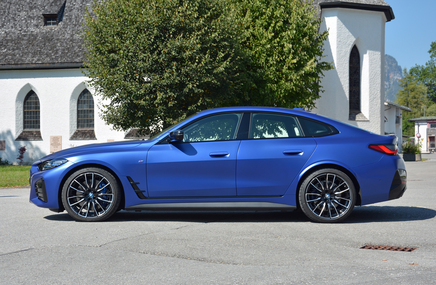 Um BMW i4 M50 2022 na calçada perto de uma igreja. 