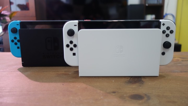 A Nintendo Switch OLED model in its dock next to a regular Switch dock.