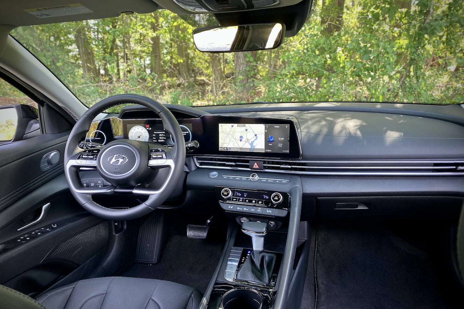 Dashboard, center console, and steering wheel of the 2021 Hyundai Elantra Hybrid from the rear seats.