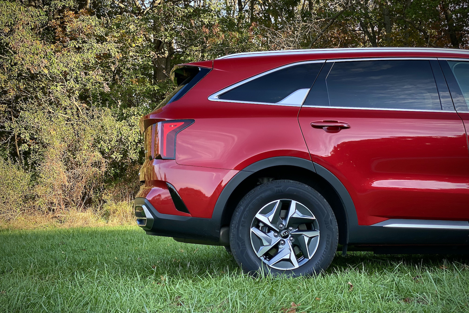 Rear half of the 2021 Kia Sorento Hybrid from the passenger side in a grassy field.