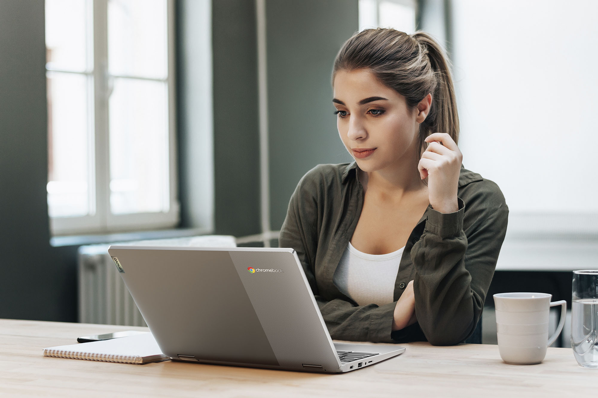 एक महिला खुले Chromebook लैपटॉप के सामने बैठी है।