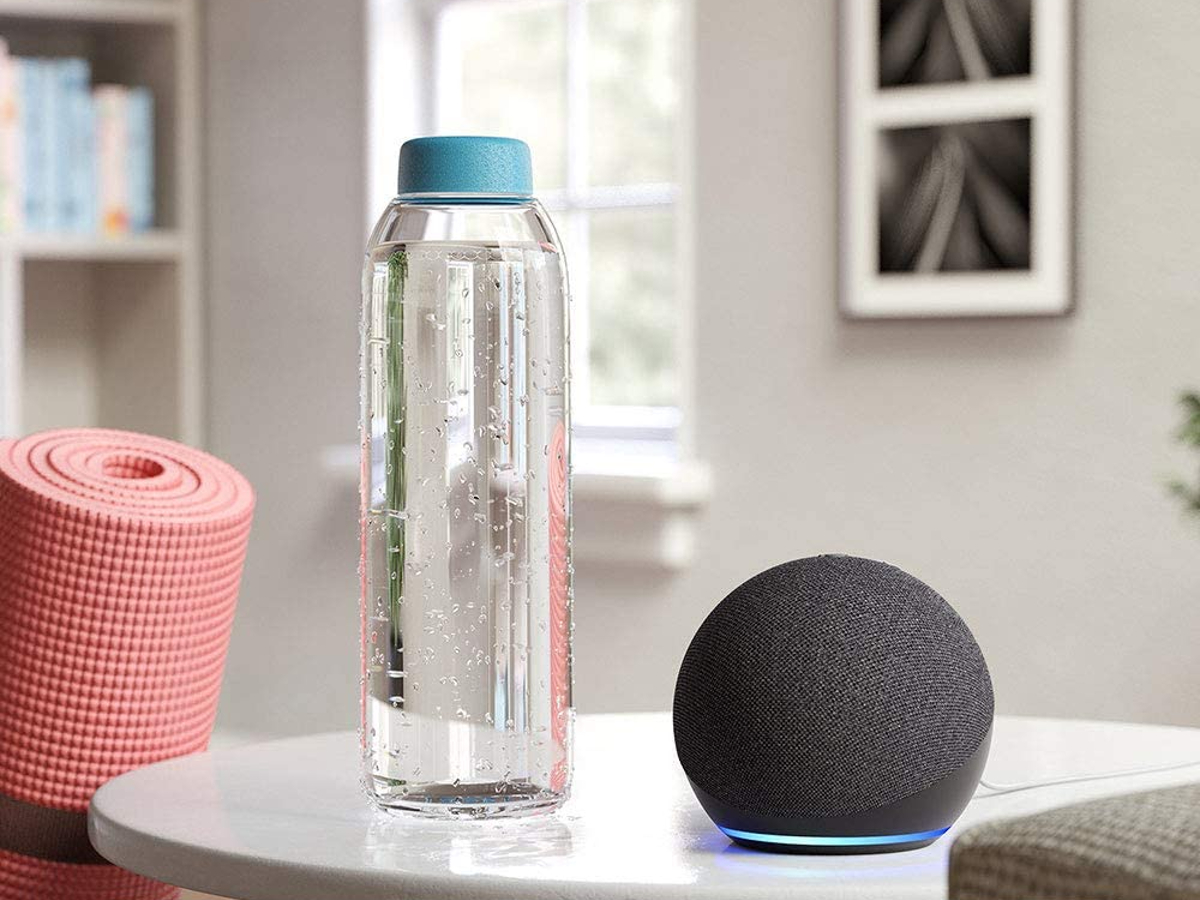 Amazon Echo Dot (4ª geração, versão 2020) em uma mesa com um tapete de ioga e uma garrafa de água.