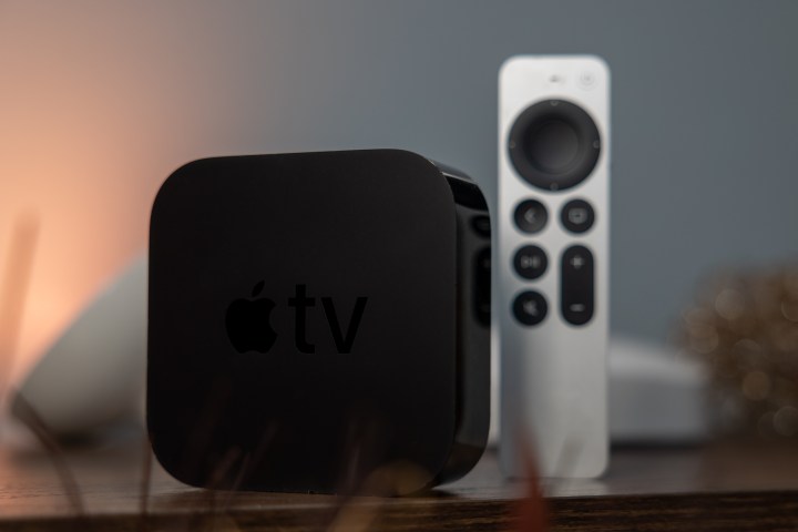 An Apple TV 4K sits upright next to a remote on a table.