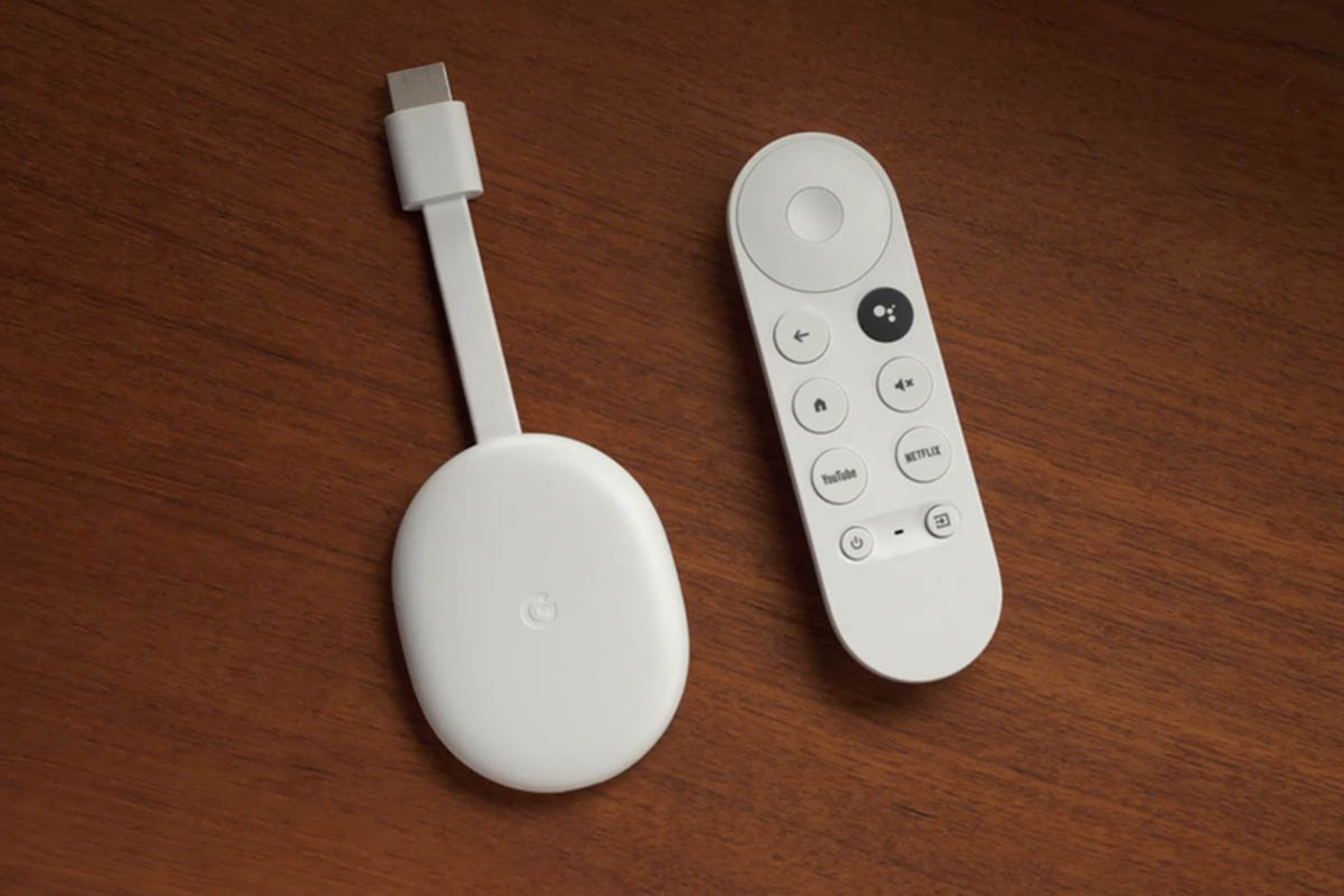 A white Chromecast and remote lie on table.
