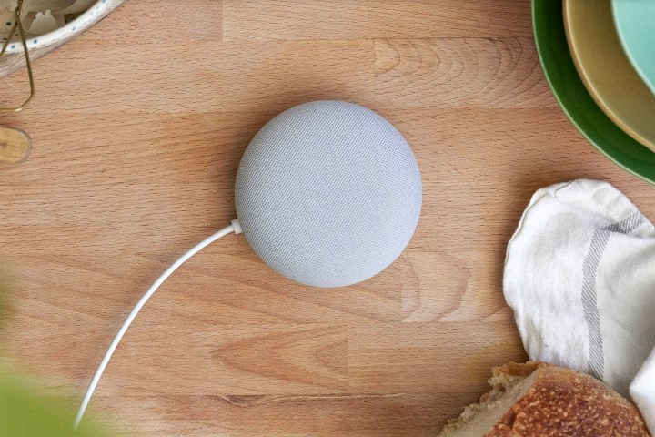 A gray Google Nest Mini sitting on a kitchen counter top.