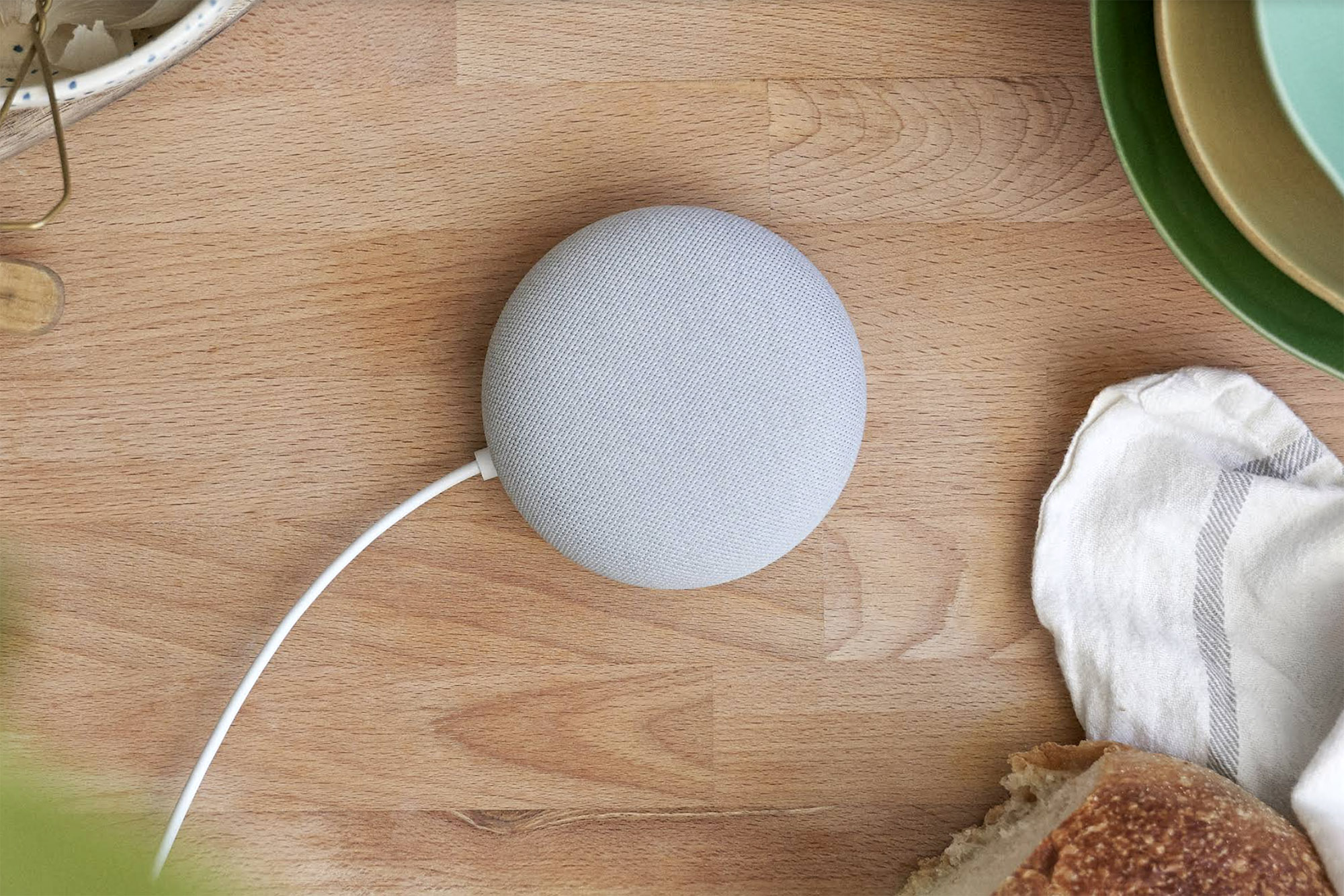 Um Google Nest Mini cinza sobre a bancada da cozinha.