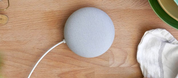 A gray Google Nest Mini sitting on a kitchen counter top.