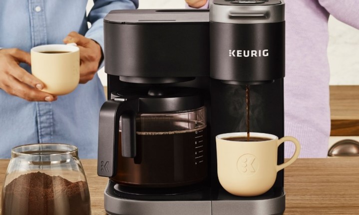 Keurig K-Duo coffee maker with a cup of coffee and two people standing behind it.