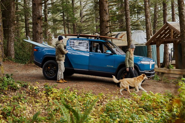 Des gens et un chien debout devant une camionnette électrique Rivian R1T.